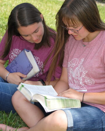 Teens reading the Bible together outside